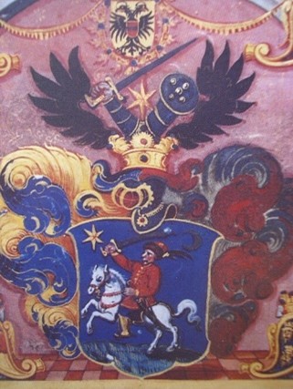 Obiteljski grb Ritterovih nakon što im je Ferdinand III. za zasluge o borbama s Turcima 1652. dodijelio nasljednu plemićku titulu baruna. Ono ranije praplemstvo koje je obitelj imala još u Alzasu ovdje se ne spominje: putujući vitezovi ili profesionalni vojnici nisu sa sobom nosili povelje kojima bi se to moglo dokazati. U gornjem dijelu grba nacrtana ruka oklopnika s uzdignutim mačem postala je sastavnim dijelom grba našeg Društva. Neki autori navode da je grb iscrtao sam Vitezović što je malo vjerojatno jer se opis grba u pravilu nalazio već u samoj povelji o dodjeli plemstva.